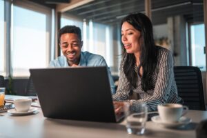 An employee showing an intern how to do a project in the office